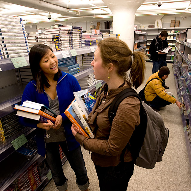 Two students picking out text books in the bookstore. 